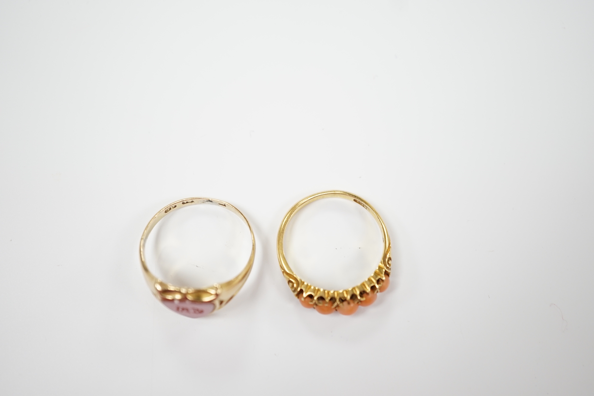 An early 20th century 18ct and graduated five stone split coral bead set half hoop ring, size O and a Victorian 12ct gold and sardonyx set shield shaped signet ring, size Q.